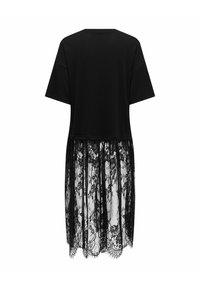 Čierne šaty s krátkymi rukávmi, snújúc solidný vrch a priehľadnú čipkovanú sukňu s kvetinovým čipkovaným vzorom, ktorá siaha pod kolená, pohľad zozadu.