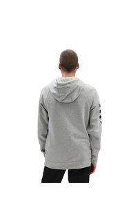 Sudadera gris con capucha y ajuste holgado, con dobladillo y puños acanalados, y rayas negras en la manga derecha.