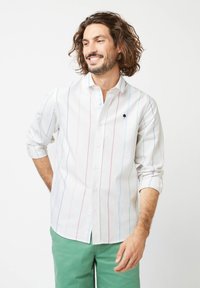 Witte overhemd met verticale pastelstrepen in blauw, roze en lichtgroen. Voorzien van een klein zwart boompje logo op de borstzak.