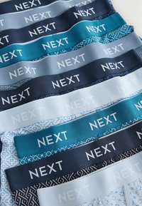 Lenjerie de corp tip boxer pentru bărbați, stivuită, cu benzi elastice în talie, în nuanțe de albastru, gri și alb, fiecare având numele brandului "NEXT" scris cu litere îngroșate.