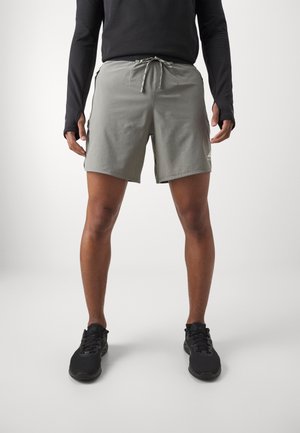 Helle graue Shorts mit elastischem Bund und Kordelzug, ausgestattet mit Seitentaschen und geradem Schnitt, kombiniert mit schwarzen Sportschuhen.
