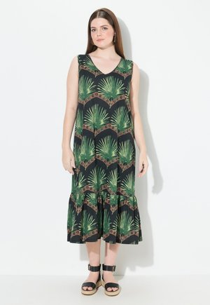 Robe sans manches noire avec imprimé de feuilles de palmier vertes, décolleté en V et ourlet à volants en couches. Associée à des sandales à plateforme noires.