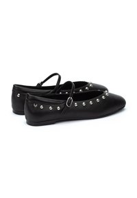 Bailarinas de cuero negro con punta afilada, que presentan una correa, acentos de tachuelas plateadas a lo largo de la parte superior y una suela plana.