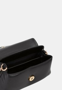 Borsa in pelle nera con texture liscia, dotata di chiusura centrale con bottone dorato e due scomparti interni. Dettagli in metallo dorato.