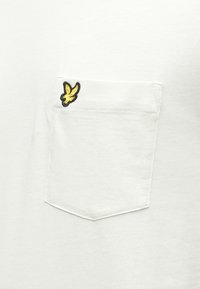 White cotton T-shirt featuring a chest pocket with an embroidered yellow and black logo and a smooth texture.