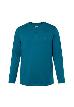 Langarm henley shirt in teal. Voorzien van een knopenlijst met drie knopen, ronde halslijn en subtiel logo op de borst. Zacht katoenmateriaal.