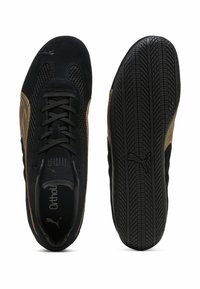 Scarpe sportive nere e dorate con tomaia in rete, dettagli in suede e suola in gomma testurizzata con un motivo di aderenza.