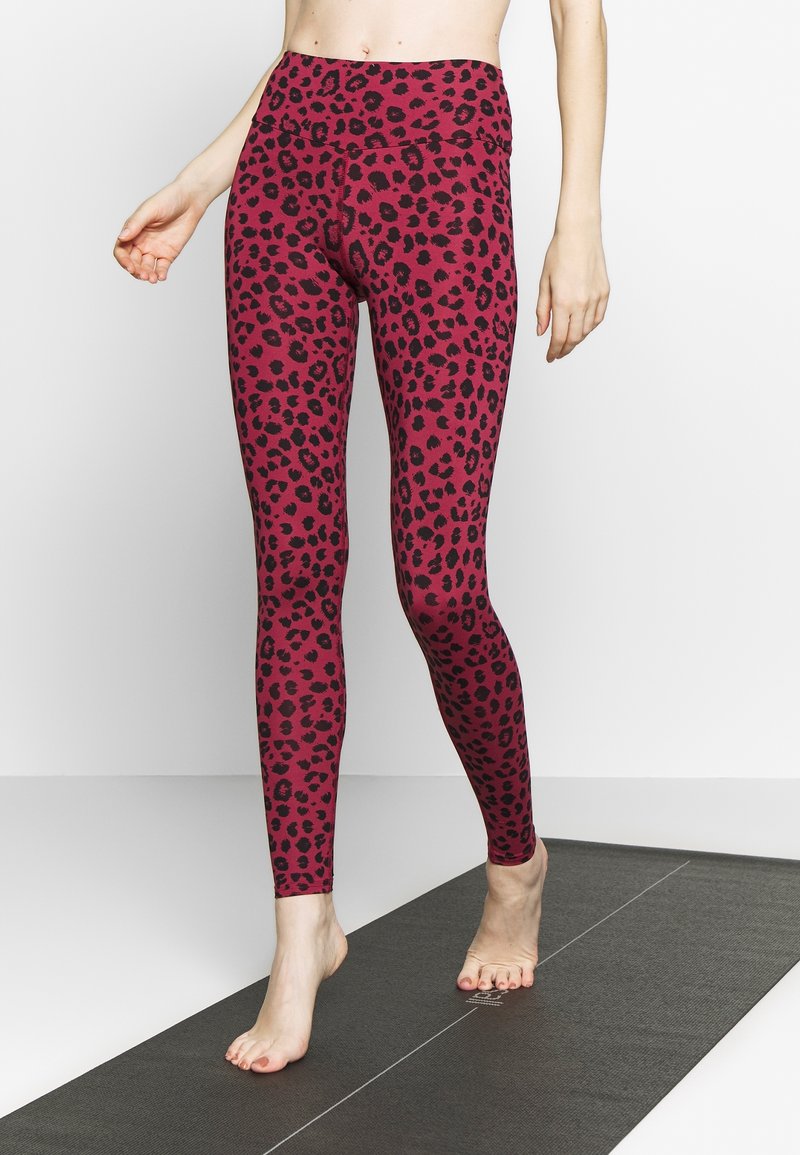 Fitte leggings in een fuchsia kleur met een zwart luipaardprint patroon. Gladde textuur, hoge tailleband en volledige lengte dekking.