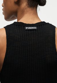 Πίσω όψη ατόμου που φοράει μαύρο ριμπ τοπ χωρίς μανίκια με ετικέτα "PINKO" στον λαιμό.