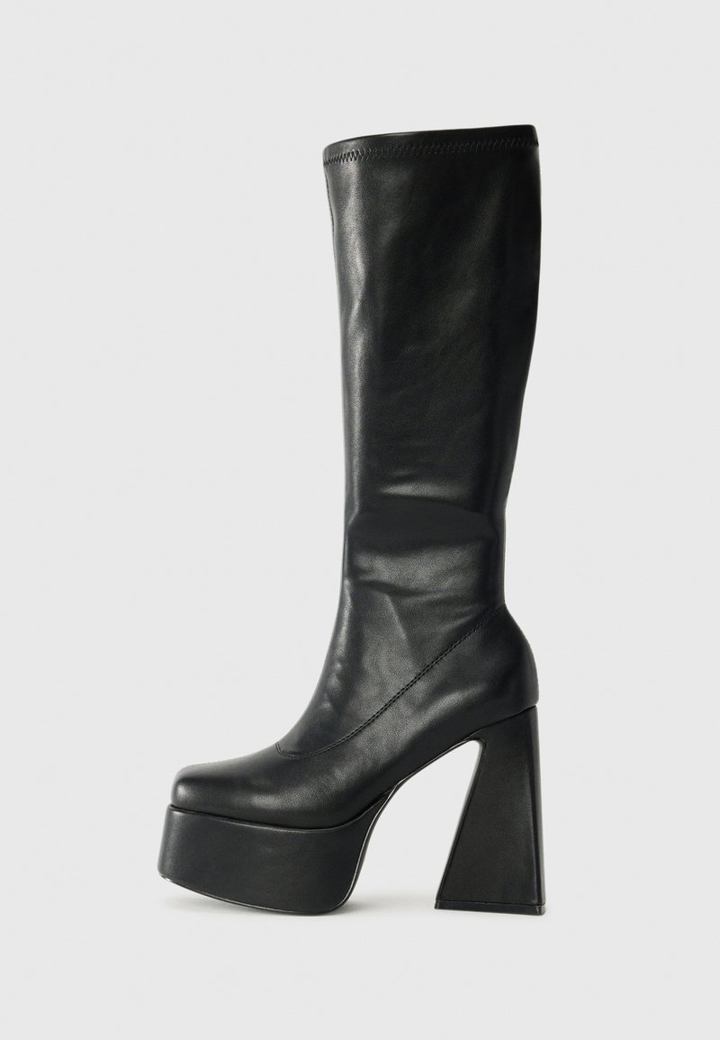 Bota de couro preto até o joelho com uma plataforma robusta e um salto alto geométrico. Textura suave com detalhes de costura na borda superior.