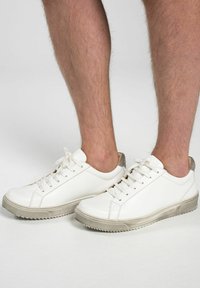 Vita lädersneakers med en beige gummisula, funktioner inkluderar runda snören, slät yta och en subtil grå accent vid hälen.