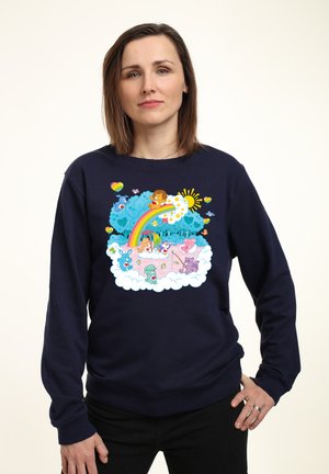 Marineblå sweatshirt med et farverigt tegneserieagtigt grafisk design, der viser skyer, en regnbue og forskellige legesyge dyr i en fantasifuld scene.