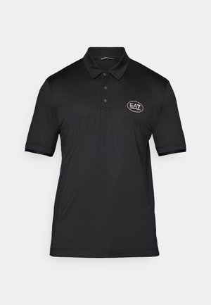 Črn polo majica iz teksturirane tkanine, ki ima tri gumbe na sprednji strani in majhen bel logotip na levi prsni strani. Kratki rokavi.