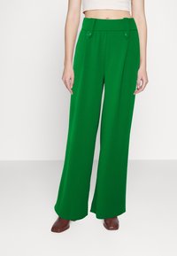 Pantalon vert à jambes larges en tissu lisse, avec devant plat, détails de boutons et taille haute.