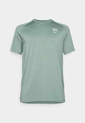 Zaļš sporta T-krekls, izgatavots no gludas, vieglas auduma. Tam ir īsas piedurknes, apaļa kakla izgriezums un diskrēti logotipa akcenti uz krūtīm.