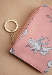 Portafoglio rosa con zip, caratterizzato da un design con cherubino, hardware dorato e attacco per portachiavi. Realizzato in tessuto testurizzato con grafiche dettagliate.
