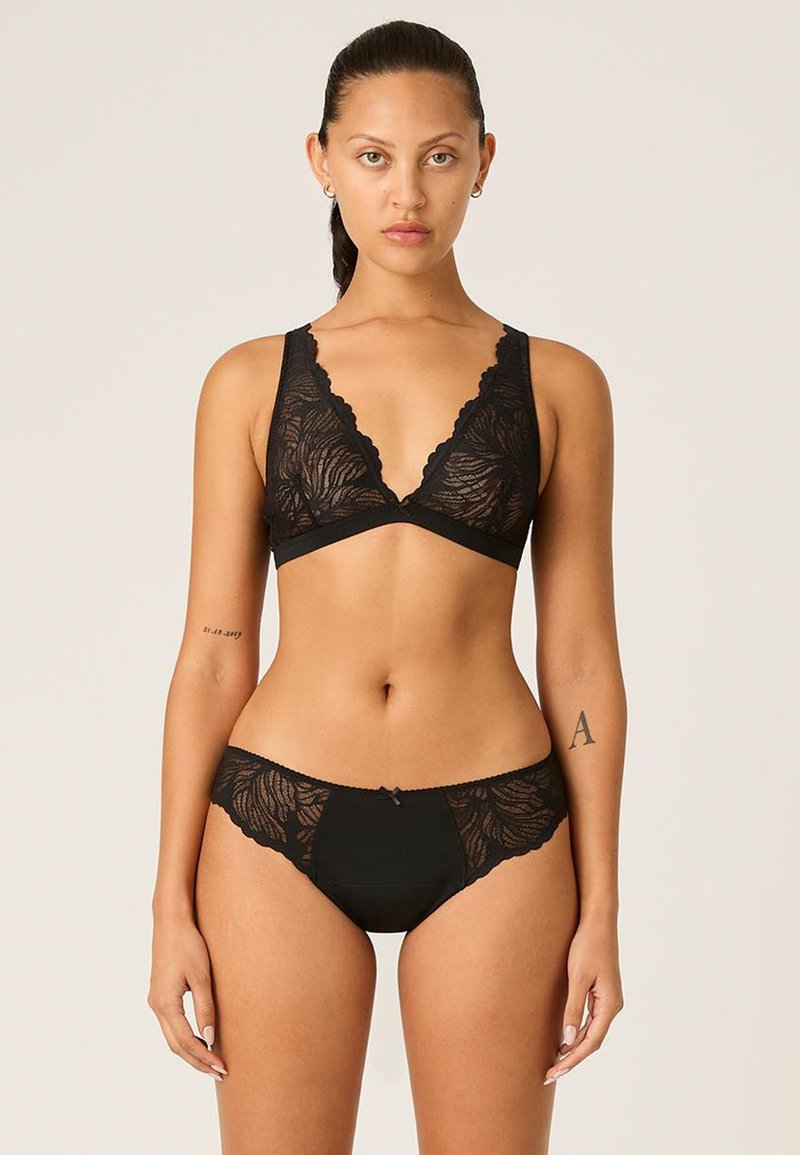Bralette en dentelle noire avec motif floral, décolleté en V et bords festonnés, associé à un bas de bikini en dentelle assorti avec détail en nœud.