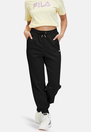 Pantaloni jogger neri con vita regolabile e tasche laterali, abbinati a una maglietta croata gialla con un logo FILA multicolore.