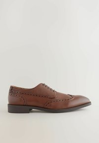 Chaussure à lacets en cuir marron avec une tige texturée, des détails brogue, un bout pointu et un petit talon empilé.
