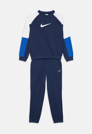 Tummansininen liikuntasuunnistus, jossa on valkoiset ja siniset väri-blokatut hihat, varustettuna valkoisilla Nike-logolla rinnassa ja vasemmassa reidessä.