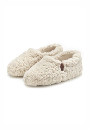 Cream-colored slippers with a fluffy texture and soft fabric, featuring a cozy design and a small leather accent on the side.