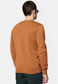 Brązowy sweter z dzianiny z okrągłym dekoltem, prążkowanymi mankietami i talią, o gładkiej fakturze i luźnym kroju, pokazany od tyłu.