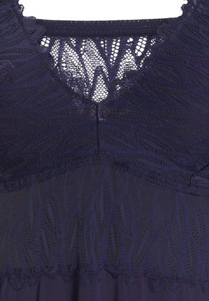 Navy dress featuring a lace bodice with a scalloped neckline and textured leaf patterns. Smooth fabric below the waist provides contrast.