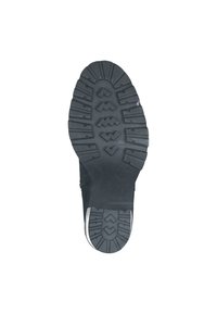 Black rubber shoe sole with pronounced tread patterns, including zigzag and triangular shapes, for enhanced grip and stability.