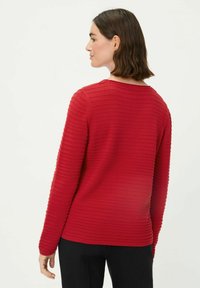 Rode trui met een gestructureerd horizontaal ribpatroon, ronde halslijn en lange mouwen, met een relaxte pasvorm en een effen kleur.