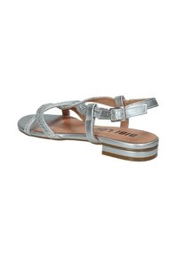Sandal in argento con design a fascia intrecciata, fibbia regolabile, tacco piatto e soletta texturizzate. Presenta una soletta solida color tan con accenti sottili.