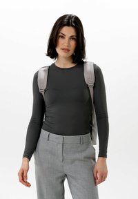 Mörkgrå långärmad topp, figurnära design, mjuk textur. Kombinerad med ljusgrå skräddarsydda byxor och en ljusgrå ryggsäck.