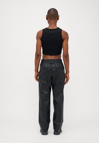 Zwart cropped tanktop gecombineerd met hoge zwarte neplederen broek, met elastische tailleband en twee achterzakken.