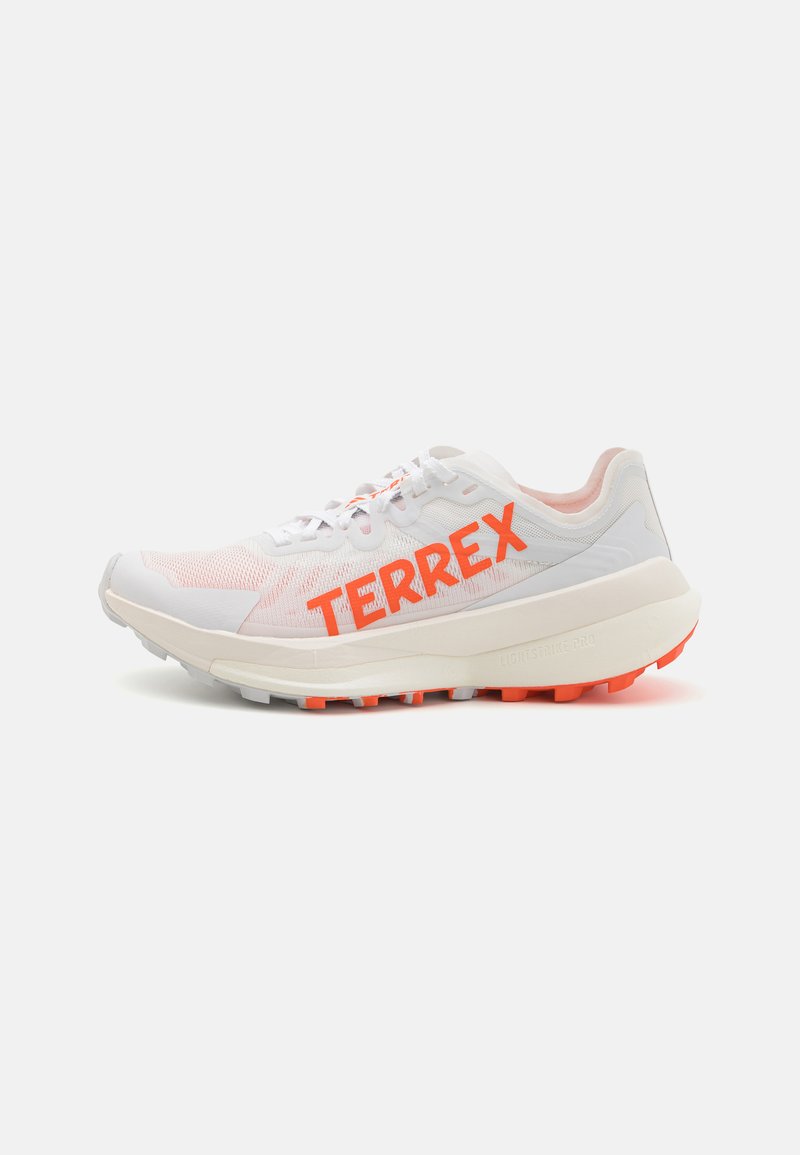 Scarpa da corsa bianca con marchio arancione "TERREX"; tomaia in rete, collo imbottito e suola testurizzata con accenti arancioni. Design leggero.