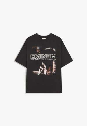 Czarny T-shirt z krótkim rękawem z grafiką mężczyzny siedzącego na schodach i tekstem "EMINEM THE MARSHALL MATHERS LP" białymi literami.