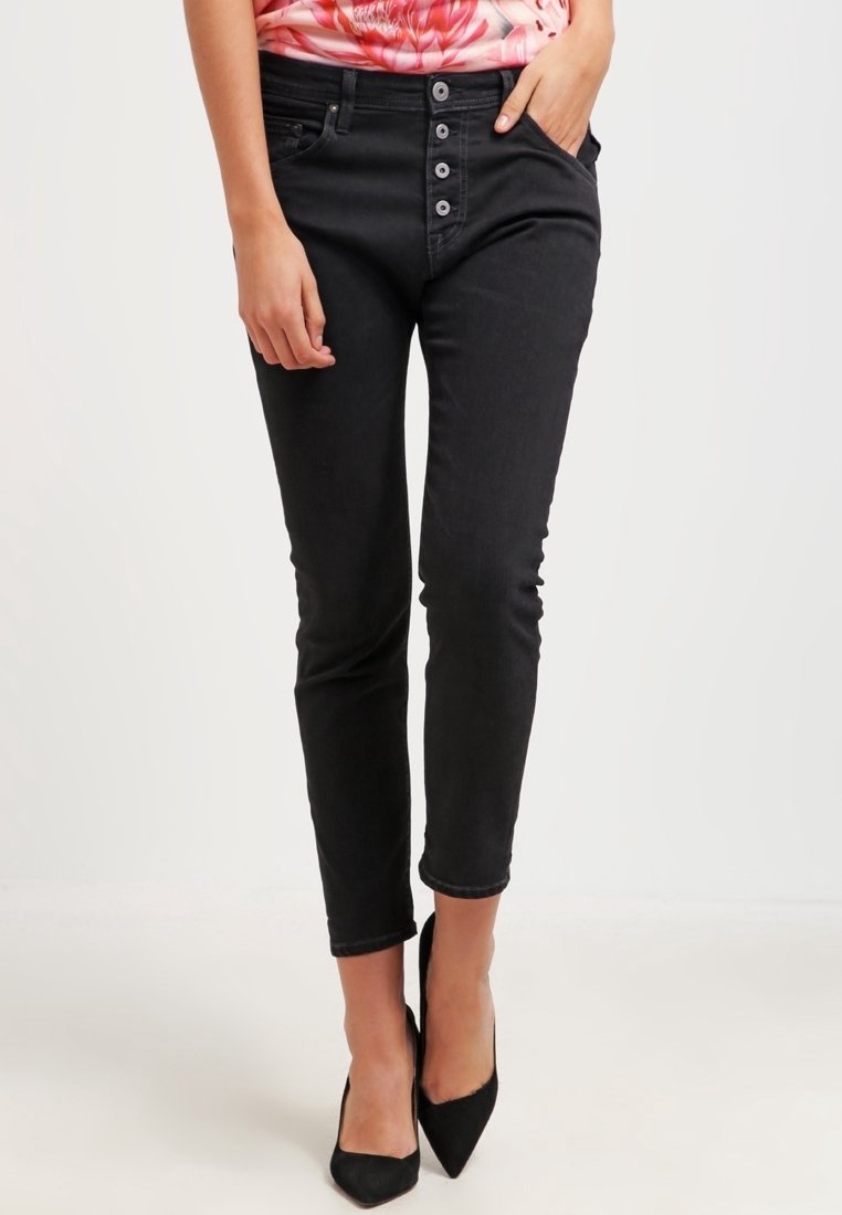 Svart denimjeans med smal passform, med hög midja, fem knäppningar och subtila urtvättningar. Matchas med spetsiga svarta klackar.