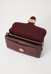 Burgundy leather bag with a gold-tone clasp, interior zip pocket, and a single external pocket. Smooth texture and structured design.