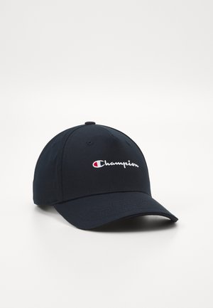 Tamsiai mėlyna beisbolo kepuraitė, pagaminta iš medvilnės, su balta siuvinėta "Champion" logotipu priekyje ir išlenktu kraštu.