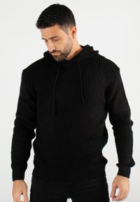 Hoodie noir en maille avec un motif textur é, doté d'une capuche à cordon et de poignets et ourlet côtelés, offrant une silhouette ajustée.