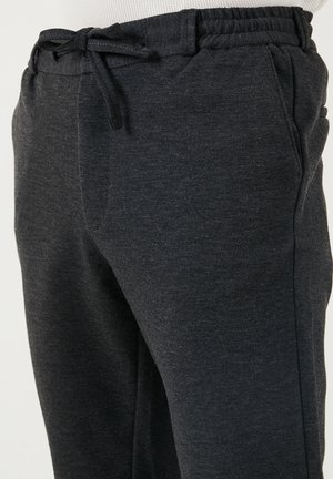 Temno sivi trenirki iz mehkega blaga, z elastičnim pasom na vrvico, stranskimi žepi in zasnovo tapered nogavic.