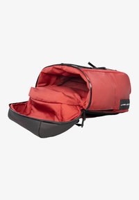 Κόκκινη υφασμάτινη ταξιδιωτική τσάντα με μαύρο κάτω μέρος, άνοιγμα με φερμουάρ και μεγάλο διαμέρισμα με εσωτερικές θήκες για οργάνωση.