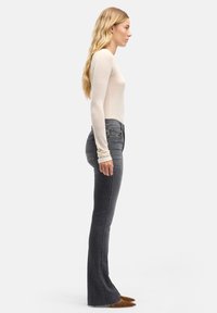 Dopasowane szare dzwony z denimu, z klasycznym pięciokieszeniowym wzorem, średnim stanem i minimalistycznymi detalami przeszyć.