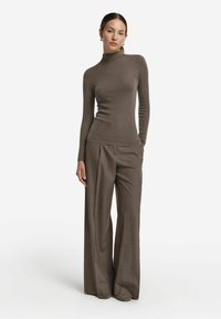 Mochaccino sweter z prążkowanym golfem i długimi rękawami, w połączeniu z wysokim stanem, szerokimi spodniami w pasującym teksturowanym materiale.