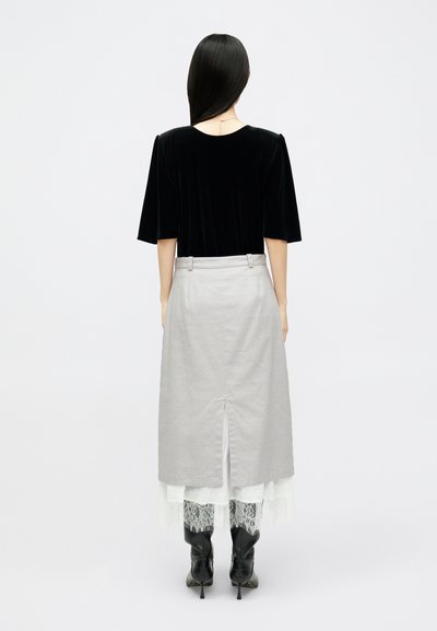 Μαύρη βελούδινη μπλούζα με κοντά μανίκια, γκρι μίντι φούστα με πίσω σχισμή, επικαλυμμένη με λευκή δαντέλα, συνδυασμένη με μαύρες μπότες μέχρι το γόνατο.