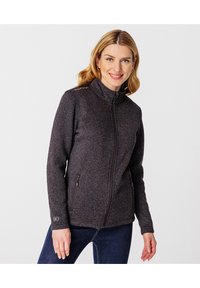 Chaqueta de forro polar negra con cierre de cremallera, cuello alto, dos bolsillos laterales y textura sutil. Presenta un logotipo en el hombro.