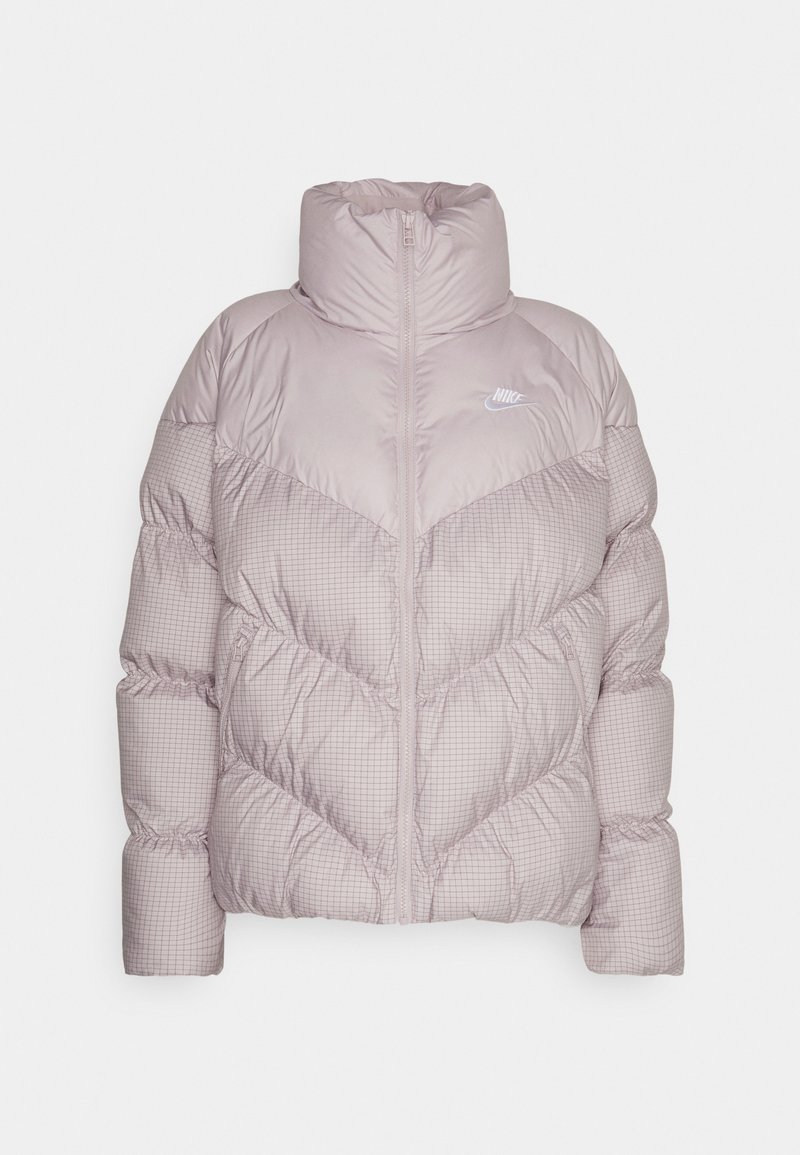 Doudoune rose clair avec un col montant, fermeture éclair et motif matelassé avec un design à carreaux subtil. Logo Nike sur la poitrine.