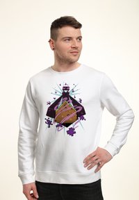Felpa bianca con una stampa grafica colorata che presenta un design a forma di diamante con accenti viola e linee vorticosi al centro.