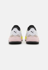 Białe i czarne sneakersy z różowymi i żółtymi akcentami. Posiadają teksturowaną podeszwę i wyściełany kołnierz. Logo Puma na panelu pięty.