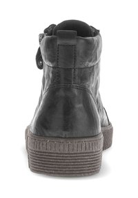 Zwarte leren enkellaars met een gestructureerde afwerking, ronde neus en een rubberen zool met horizontale ribbels. Zijrits en knoopdetail.