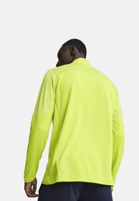 Gele sportieve langemouwshirt met een gestructureerde schouderaccenten en een gladde stof. Ontworpen met een kraag en aansluitende manchetten.