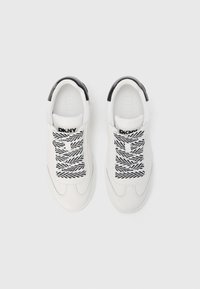 Λευκά αθλητικά παπούτσια με μαύρες λεπτομέρειες, σχέδιο με κορδόνια και κορδόνια σε ασπρόμαυρο μοτίβο. Λείο δερμάτινο υλικό και στρογγυλεμένες μύτες.